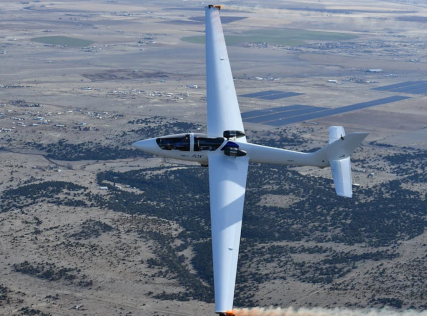 Top-down view of Bob Carlton flying a FoxJet sailplane over desert landscape during an aerobatic maneuver.