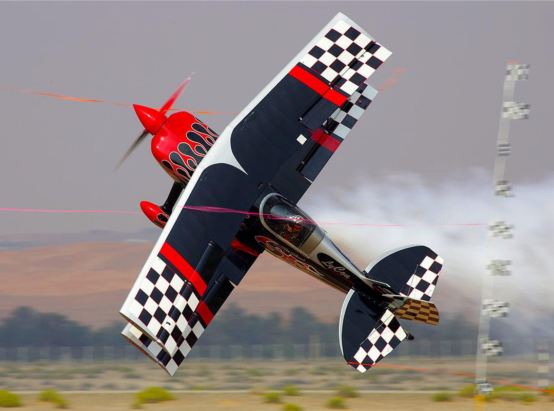 Airshow pilot Skip Stewart flying a Pitts S-2S aerobatic biplane in flight during an aerial performance.